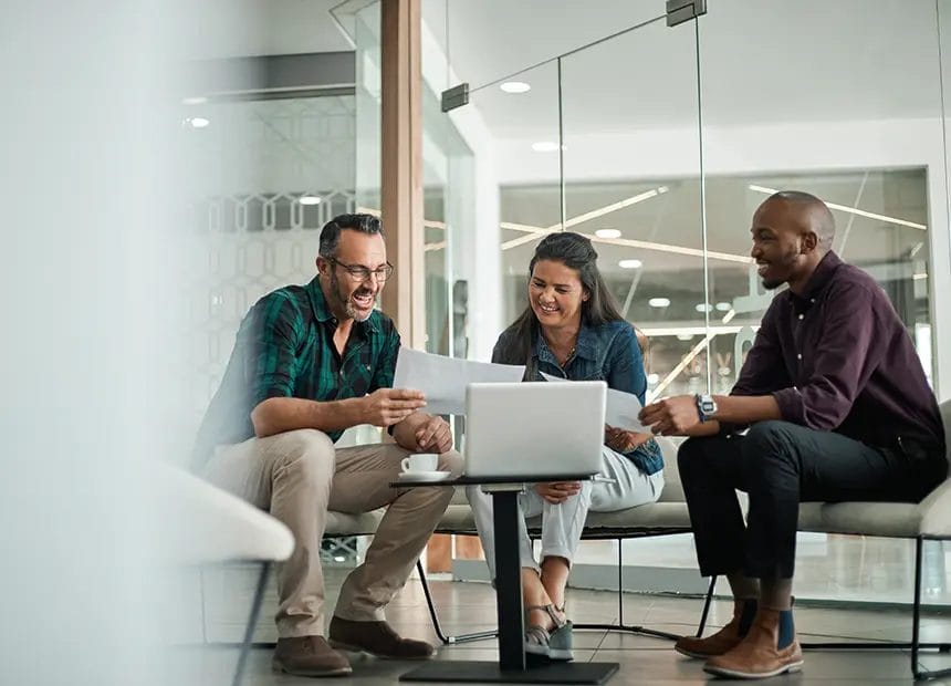 Two men and a woman in an office with laptops